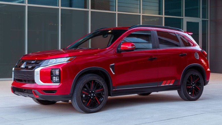 A red 2021 Mitsubishi Outlander Sport parked in front of a glass building