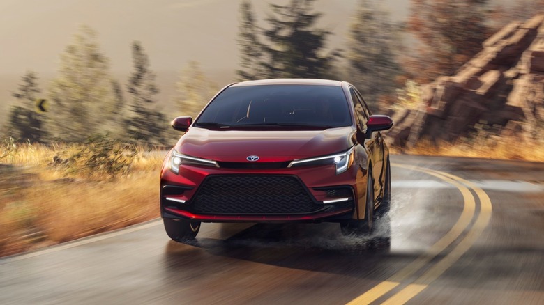 A red 2025 Toyota Corolla Hybrid cornering on a wet mountain road