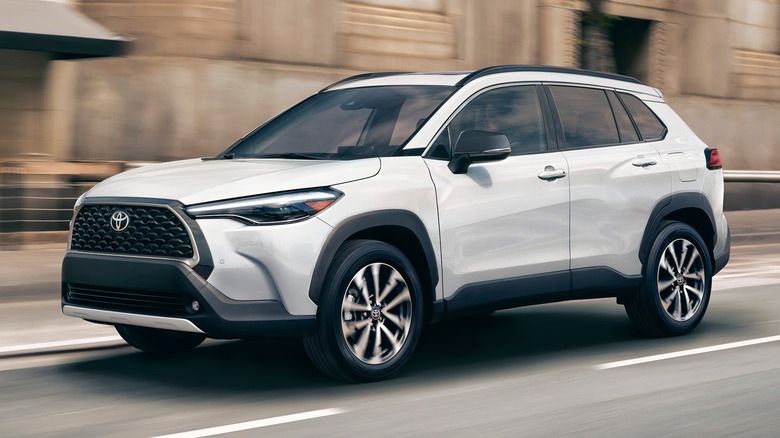 A white 2025 Toyota Corolla Cross driving on a city street