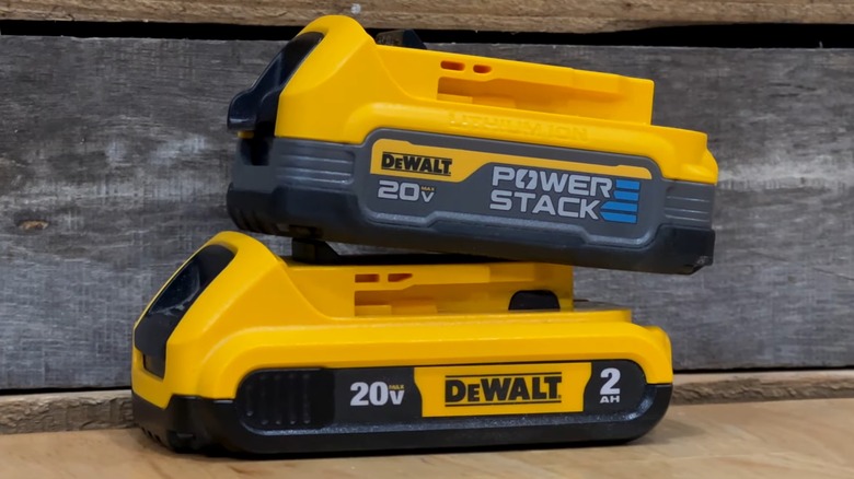 Two DeWalt batteries stacked on a wood table.
