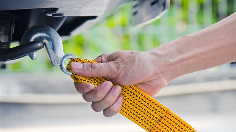 Hand holding yellow car towing strap