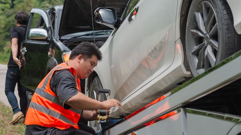 man locking wreck car in towing truck