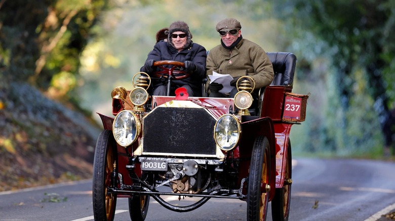 Two men driving early 1900s car