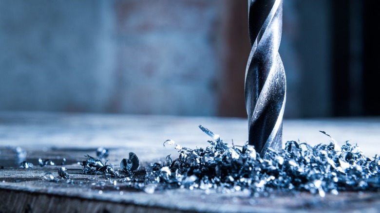 A drill bit surrounded by metal shavings after drilling into steel.