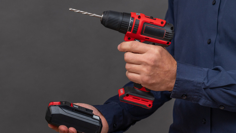 A person attaching a battery to a drill.