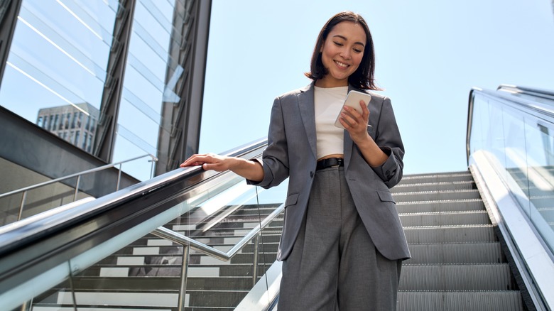 woman using phone on escalator