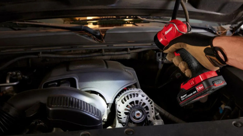 Bauer flashlight shining on car parts under hood