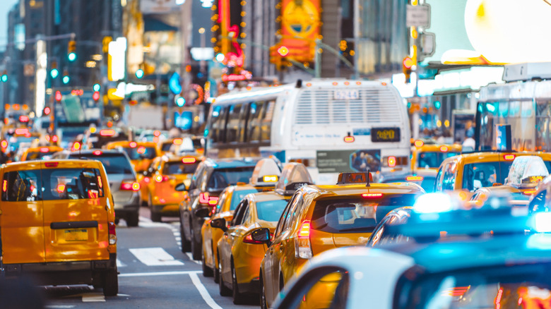 A busy multi-lane road crowded with yellow cabs, a few cars and a couple of buses.