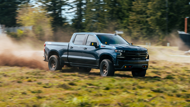 A 2024 Chevrolet Silerado 1500 Z71 finished in deep blue off-roading in a grass field.