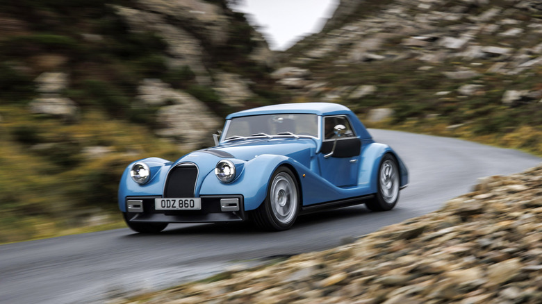 A blue Morgan Supersport on the move in the countryside, front 3/4 view