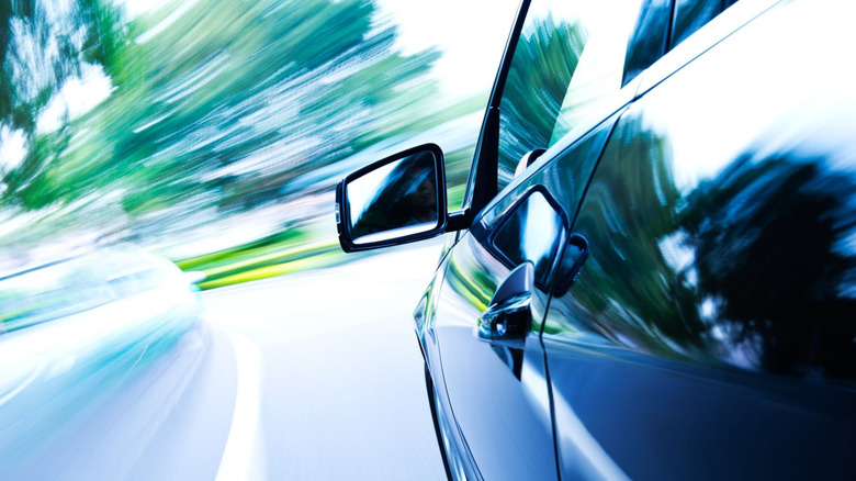 A black car driving fast on a mountain road
