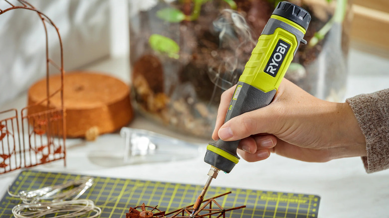 A technician holding a Ryobi USB lithium soldering pen