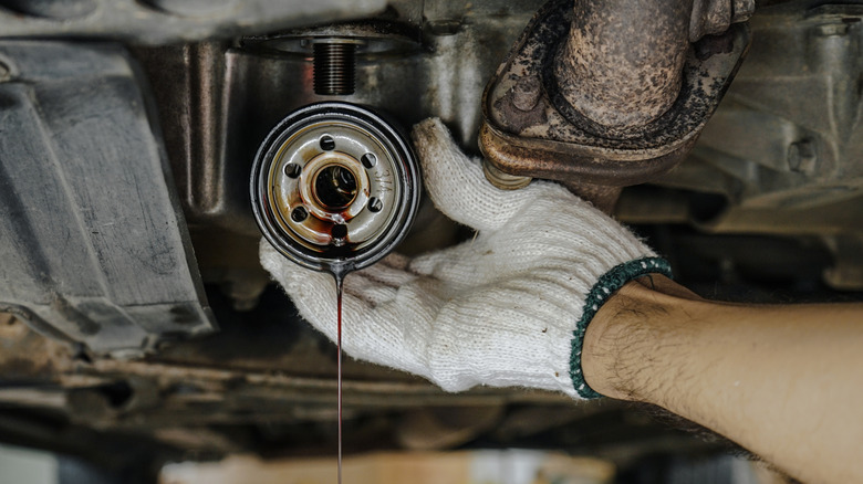 mechanic holding used car oil filter