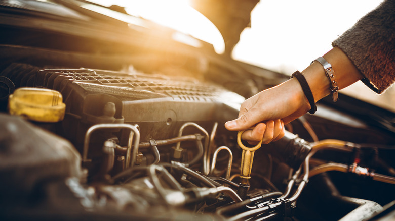 A woman examining a car's engine