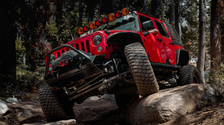 A Jeep driving over rocks in the woods