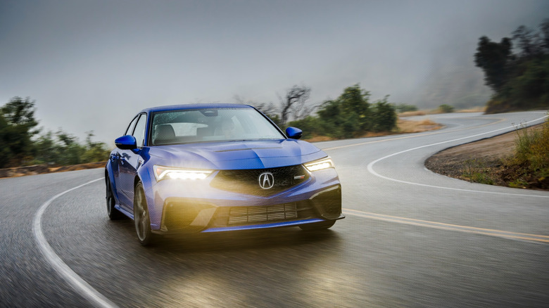 The Acura Integra Type S in blue drives down a rainy road
