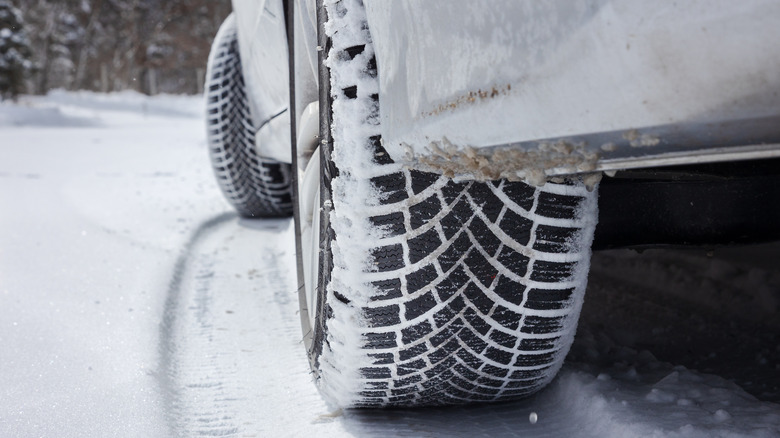 A closeup of a car's tires on a snowy road.