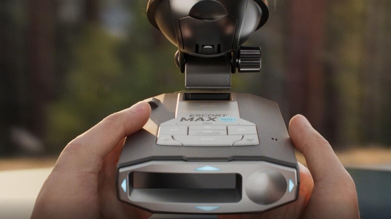 A person putting a radar detector on their windshield.