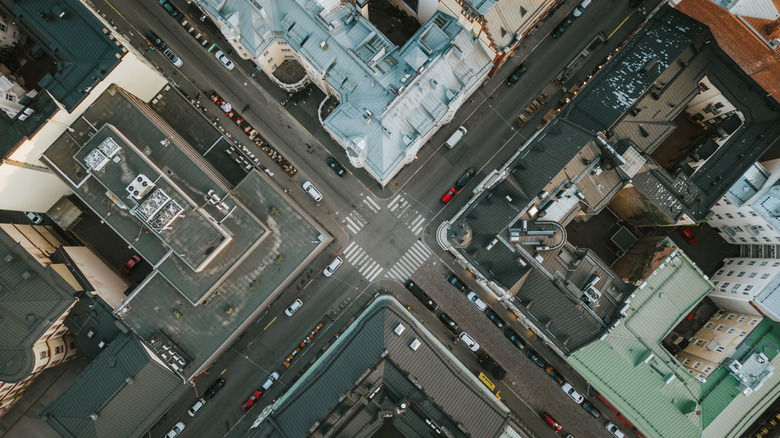Aerial view of European four-way intersection with traffic and parked cars