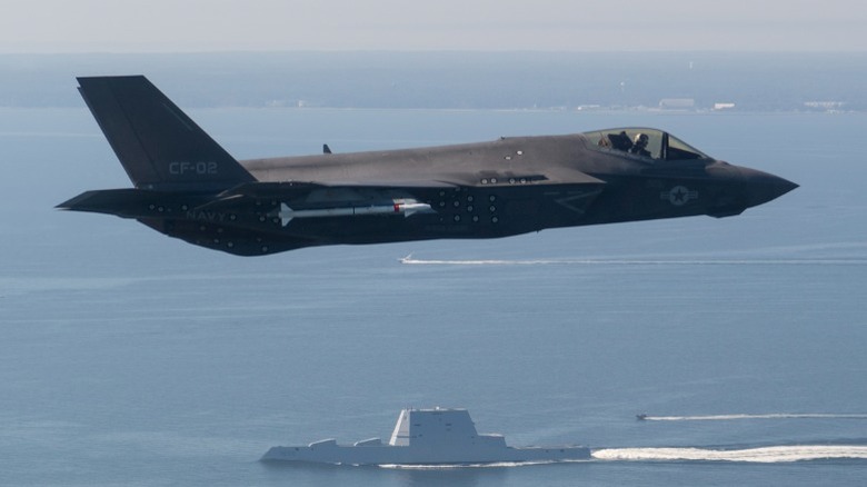 The F-35 stealth strike fighter flying over a destroyer