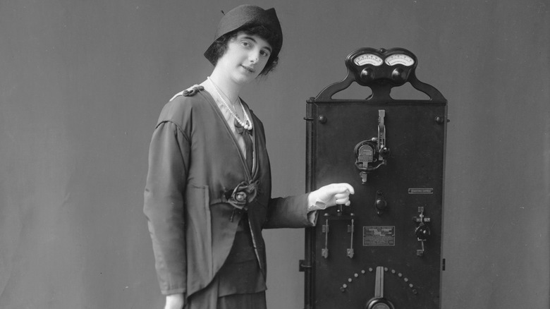 A woman standing beside an electric car charger.