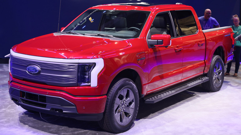A red ford F150 lightning being showcased against a deep blue background with the ford logo on it