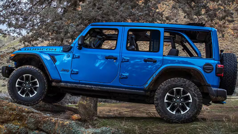 2025 Jeep Wrangler 4xe Willys edition climbing red rock terrain near a lake, doors off for open-air off-roading experience