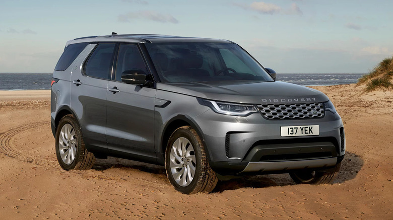 2025 Land Rover Discovery SUV parked on sandy beach with ocean view in the background
