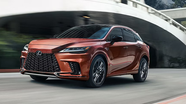 A bronze Lexus RX350 Hybrid trim zooming along a city road, with motion blur visible in the background