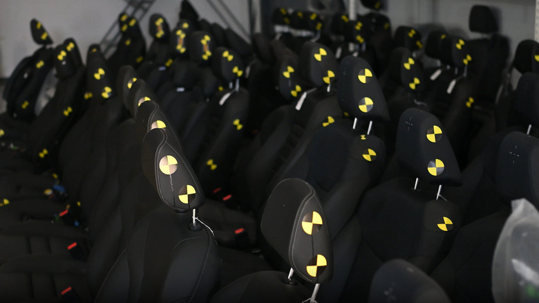 Several rows of car seats with yellow and black test disks on the headrests lined up