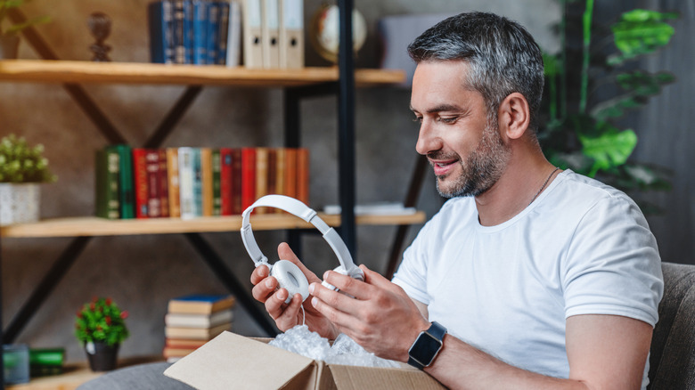 Man looking at headphones as he takes them out of the box