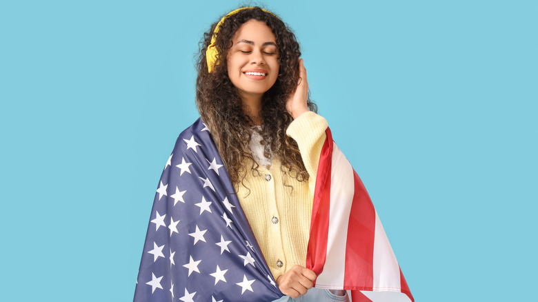 Woman wrapped in American flag wearing headphones