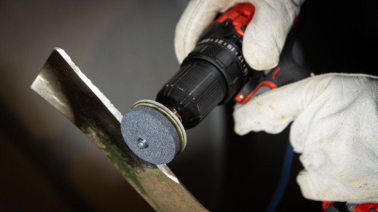 Person sharpening a lawnmower blade