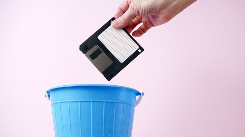 Hand dropping floppy disk into trash