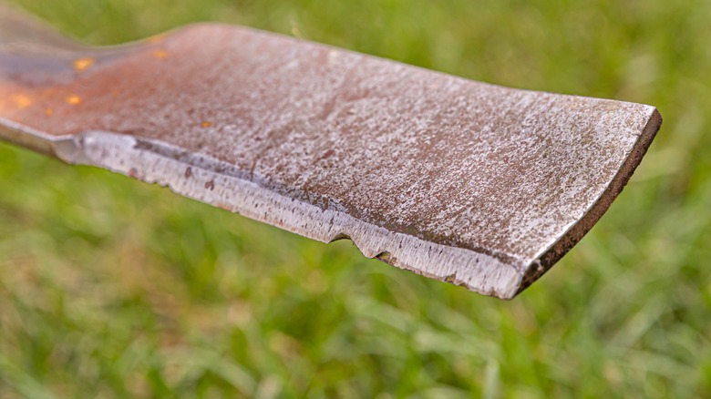 A worn lawn mower blade with gouges and pits.