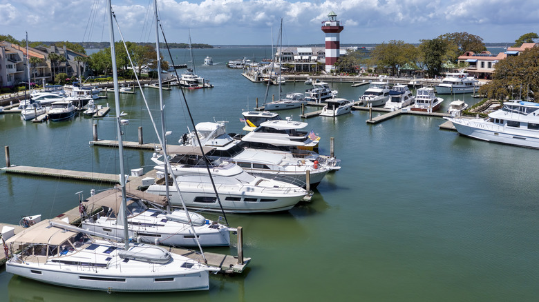 areal view of a marina with several boats docked and a lighthouse in the background