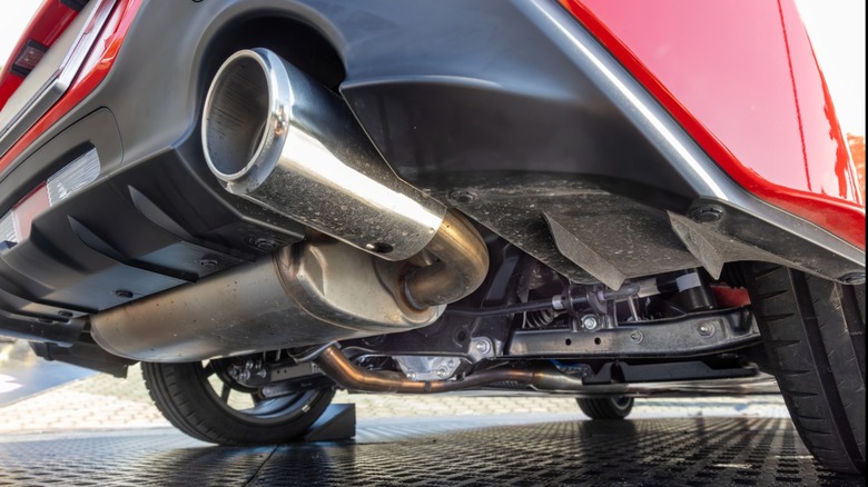 Underside of a red sports car with visible muffler and exhaust pipe
