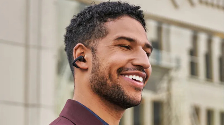 Someone in a suit wearing the Shokz OpenDots One earbuds.