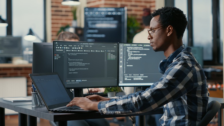 A man with his laptop and a secondary monitor