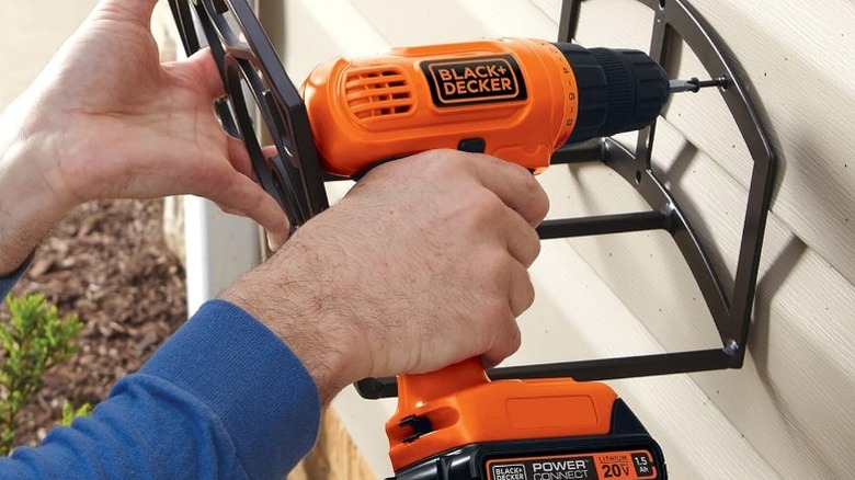 Person attaching hose rack with Black and Decker drill