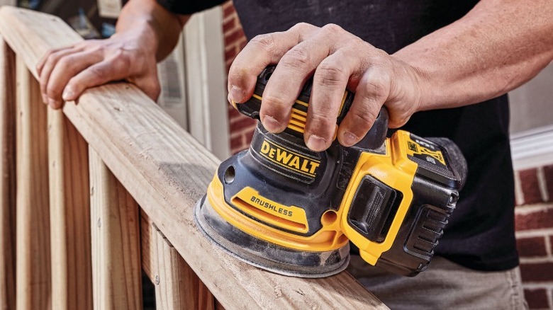 Person sanding wooden banister with DeWalt 20V Max XR 5-inch Cordless Orbital Sander