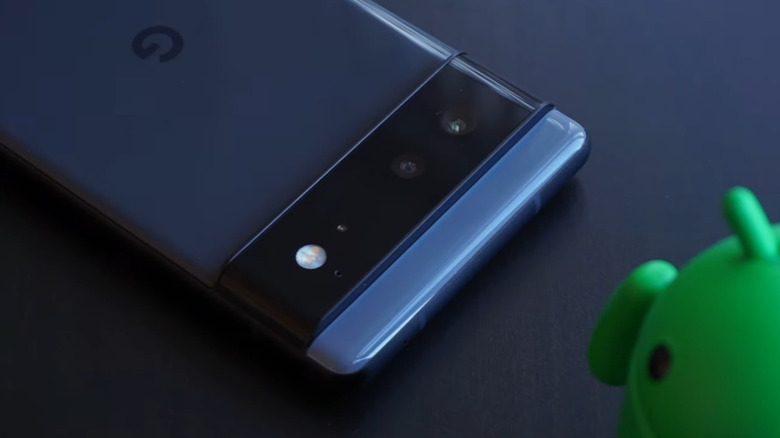 Google Pixel lying facedown on a blue surface next to a 3D model of the Android logo