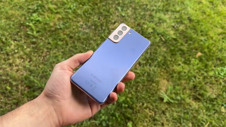 Galaxy S21 phone in a hand, grassy lawn background