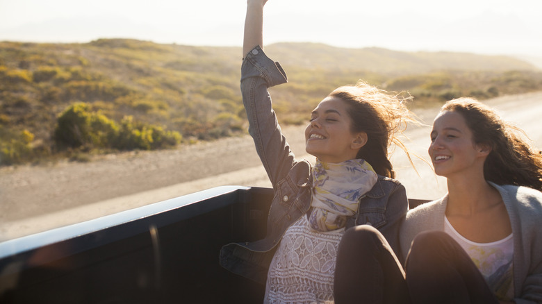 Two women sitting on the end of a pickup truck while moving