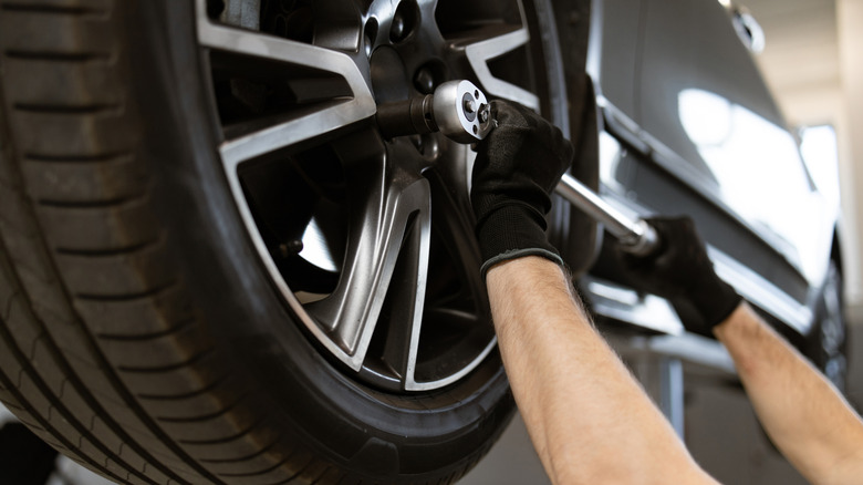 A close-up of gloved hands tightening wheel lugs with torque wrench