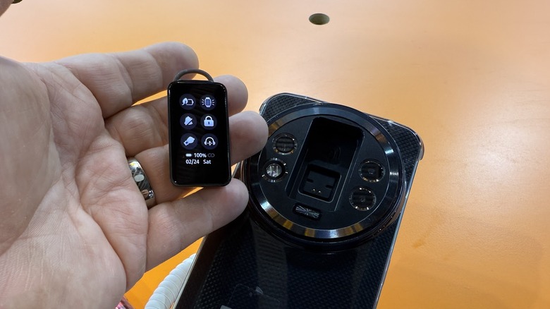 Ouketel on a table with the earpiece being held by a man