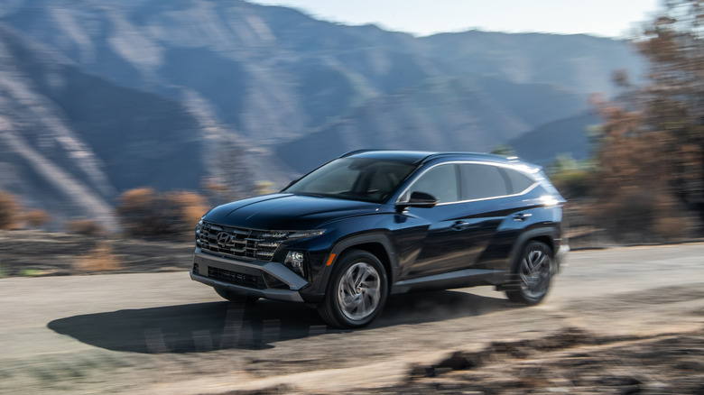 2025 Hyundai Tucson driving along mountain road, front-left 3/4 view