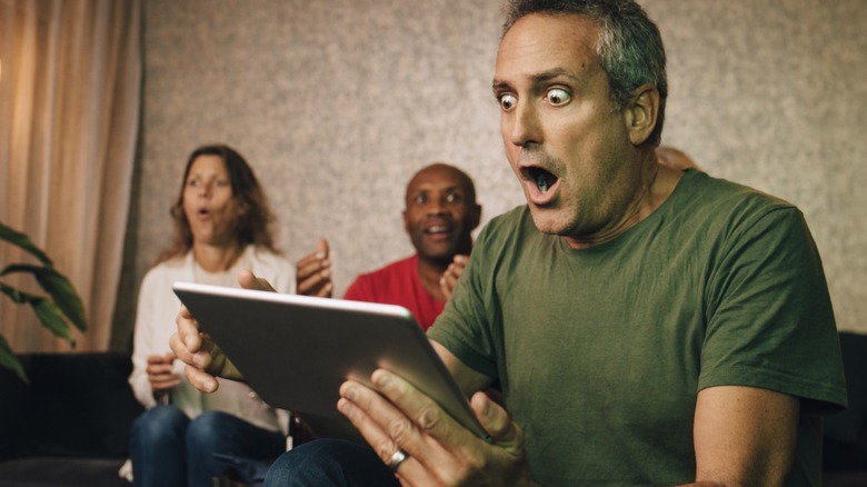 A man staring at his tablet in disbelief