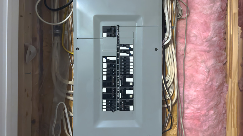 A residental circuit breaker with many cables coming out of it.