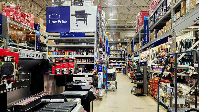 An isle inside a Lowe's store, various grills on display.